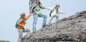 parent and children walking up a mountain together hand in hand
