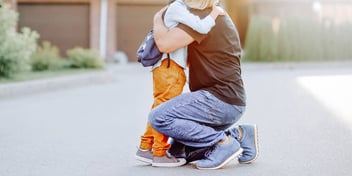 Father hugs his little boy outside his home when picking up for his shared custody