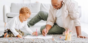 Dad and child draw together on carpeted floor