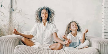 mom and daughter practicing meditation and mindfulness with yoga at home