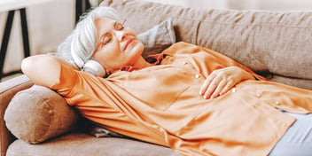 relaxed woman laying on couch and listening to music