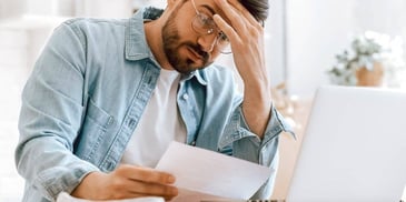 concerned man looking over bills he can't afford to pay