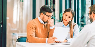 couple sitting with a mediator and reviewing paperwork