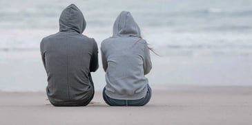 Unhappy couple sits quietly on the beach