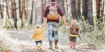 father and two children hiking together in a forest