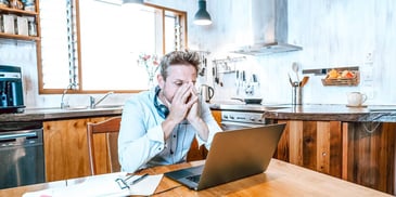 man looking at his computer in anguish trying to manage his finances