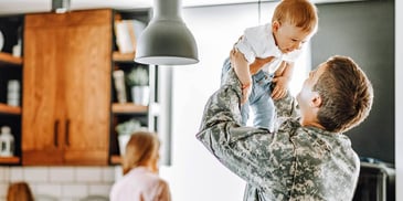 servicemember holding up his son on a visit to his ex-spouse's home