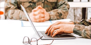 two members of the military doing paperwork and computer work