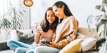 mother and daughter sitting on couch looking at phones