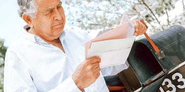 retired man looking at divorce paperwork in his mailbox