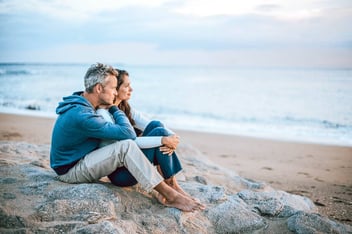 sad couple sitting together at the beach on a gloomy day