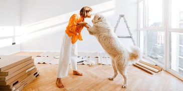 woman dancing with her golden retriever dog in her new home