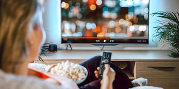 person sitting with remote control and popcorn about to watch TV