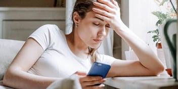 Woman looks at her smartphone stressed