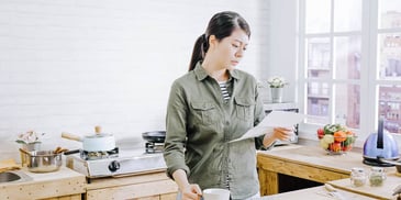 Woman looks at paperwork in her kitchen
