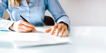 woman signing paperwork at a table