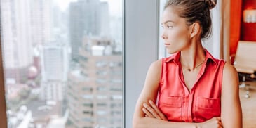 woman looking out her office window wondering how to divorce her spouse who lives abroad