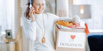 woman smiling and holding donation box while talking on phone