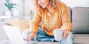 Woman with mug looks at her laptop