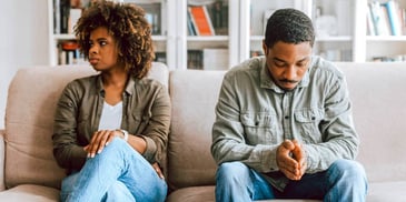 Young black couple sitting on the couch upset with one another